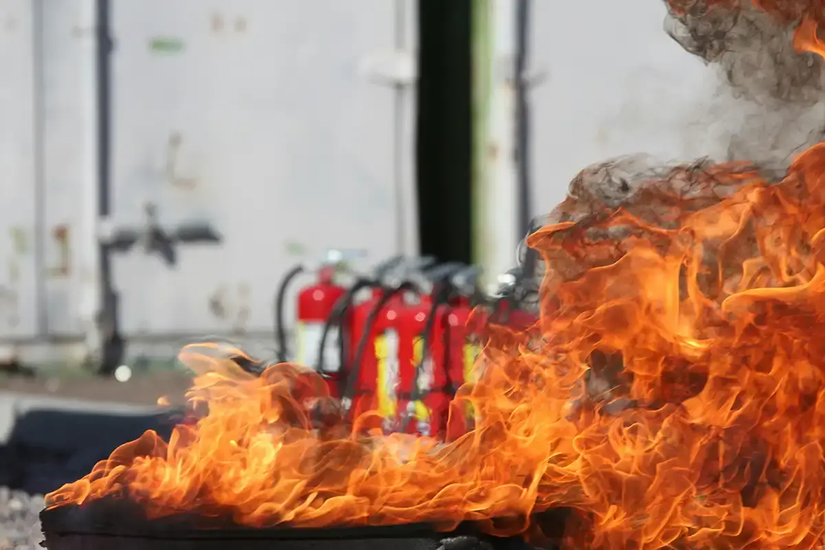 Fire infront of a row of fire extinguishers